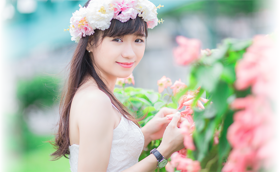 女性が自然の中で花冠をかぶってこちらに微笑んでいる写真